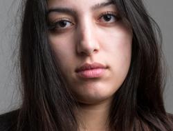 Stern young woman looks into camera.
