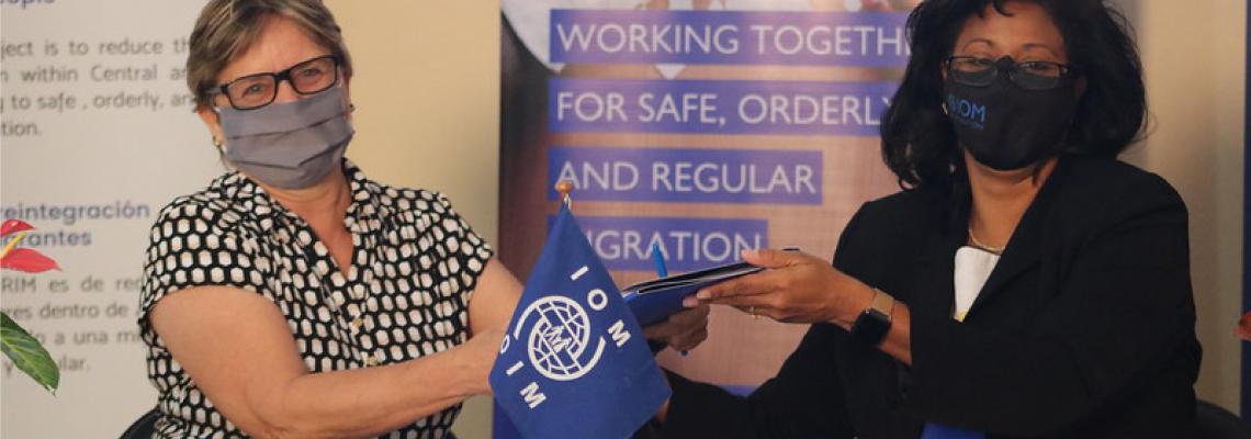 Dos mujeres con mascarilla sostienen el acuerdo recién firmado