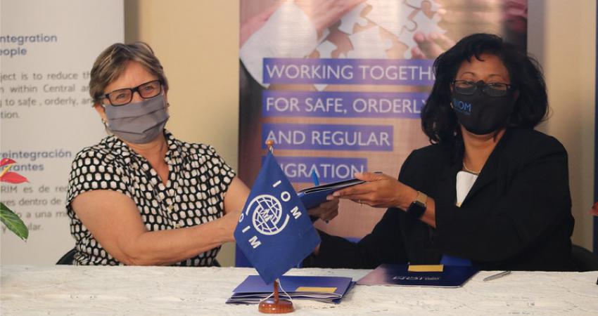 Dos mujeres con mascarilla sostienen el acuerdo recién firmado