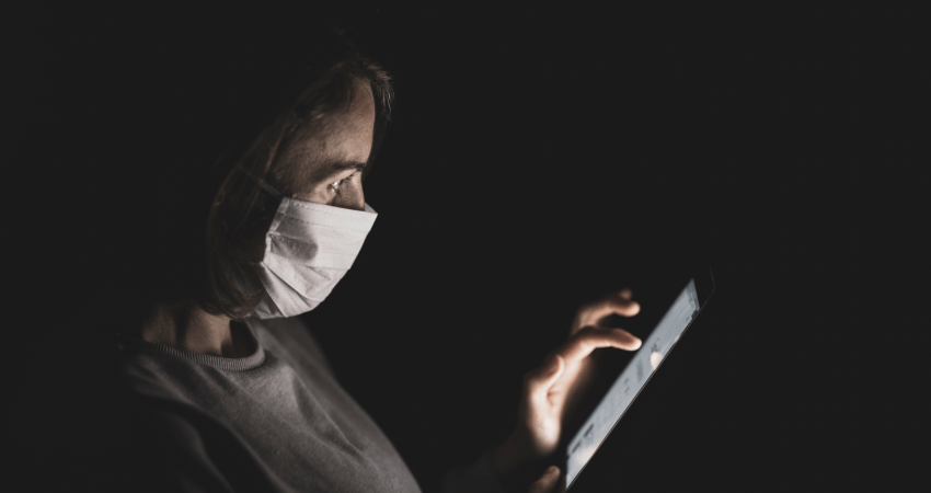 Person with surgical mask reads information on mobile device