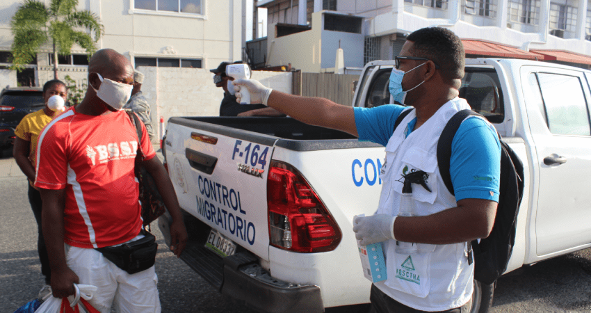 Official checks migrant's body temperature before his repatriation